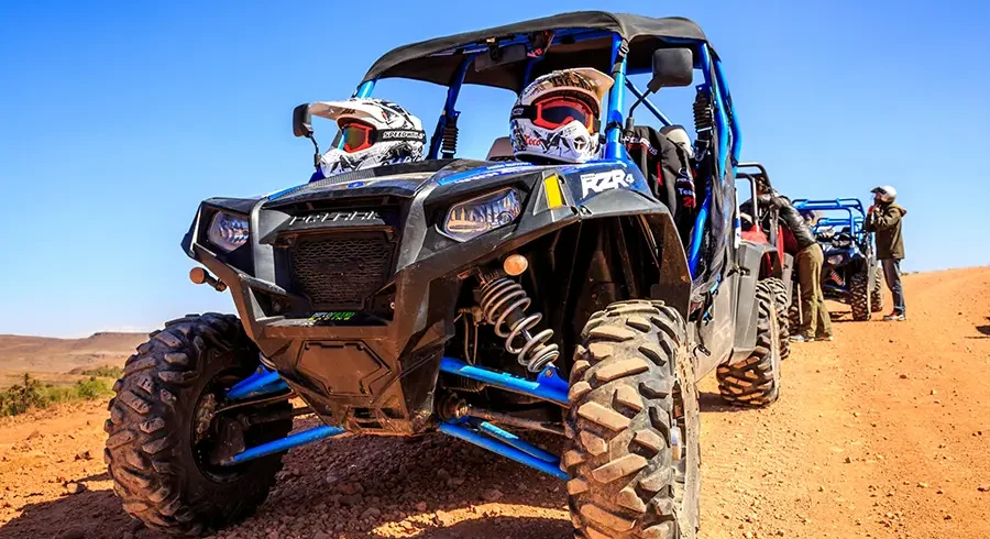 Buggy driving across Agafay desert under a clear blue sky
